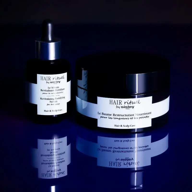 To mørke beholdere med teksten "HAIR rituel by Sisley Paris". 