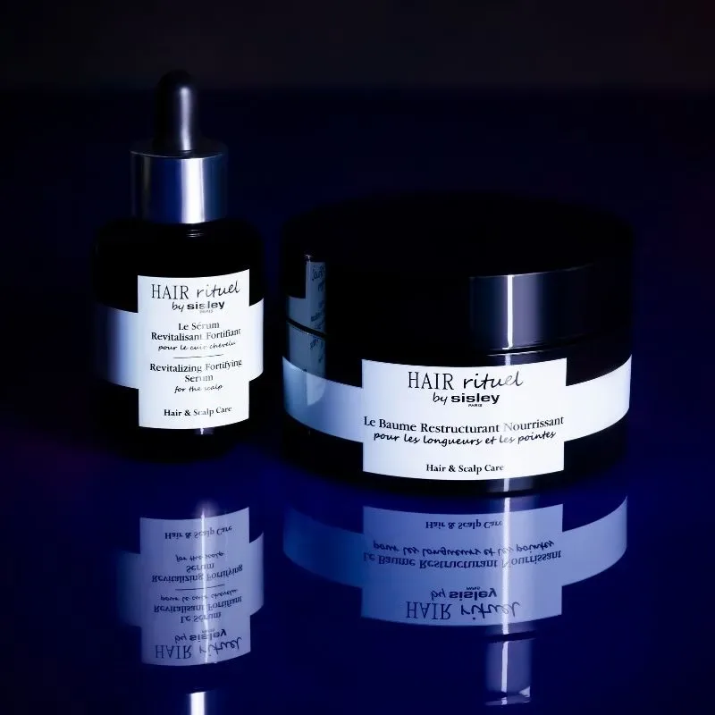 Två mörka behållare med texten "HAIR rituel by Sisley Paris". 