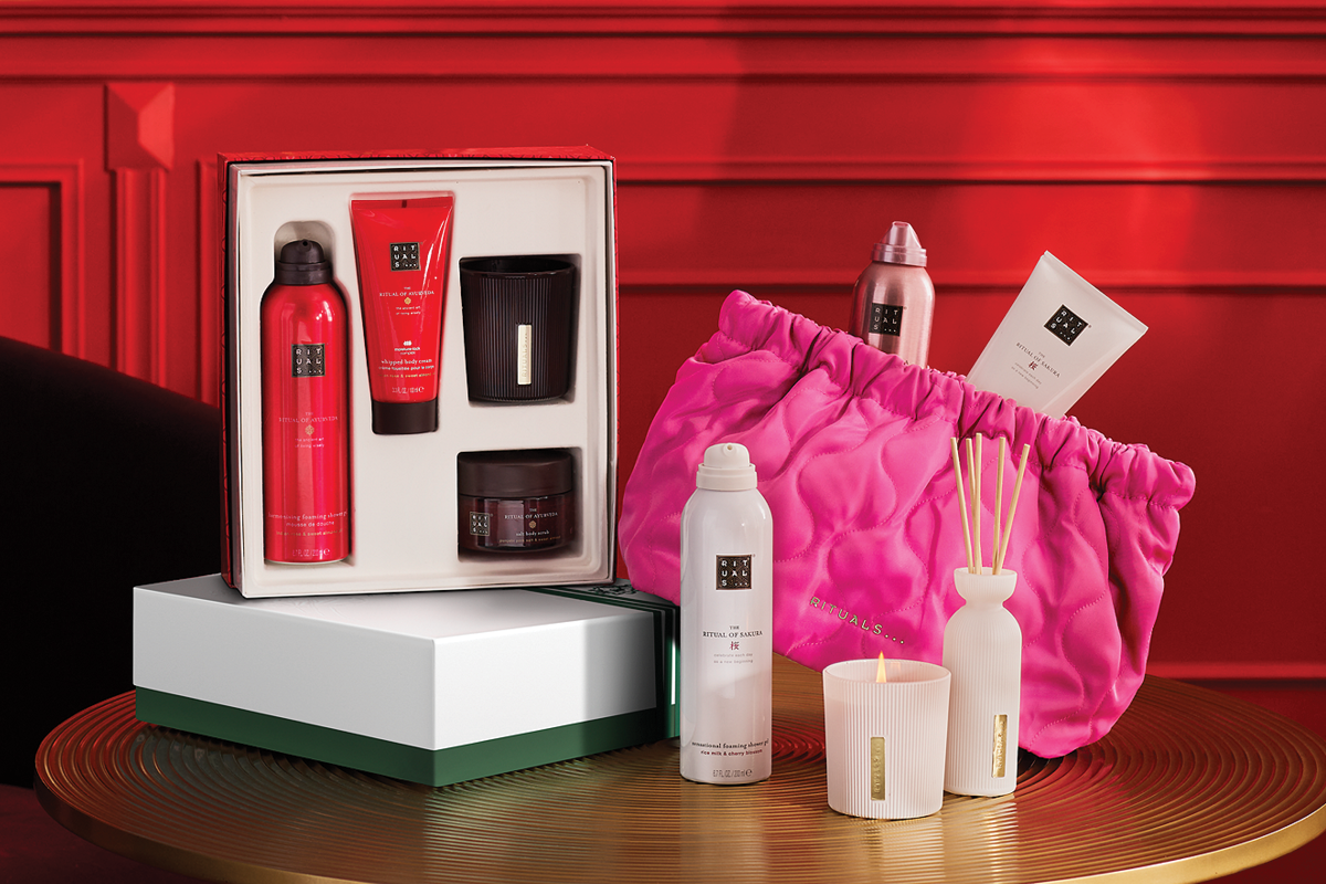 Rituals gavesett som inneholder dusjgelé, kroppskrem, skrubbekrem og et svart lys. Ved siden av står en rosa Rituals-pose, en hvit dusjgelé, et hvitt lys og en duftpinnerbeholder.