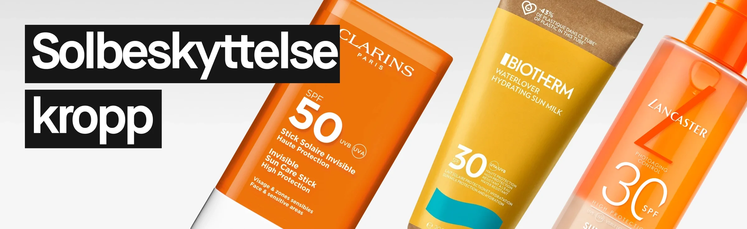 Tre solbeskyttelsesprodukter for kroppen mot lys bakgrunn. Til venstre vises teksten “Solbeskyttelse kropp” i hvit tekst på svart bakgrunn. Til høyre sees en oransje Clarins SPF 50 stick, en gul Biotherm Waterlover Hydrating Sun Milk SPF 30 tube og en oransje Lancaster SPF 30 pumpeflaske.