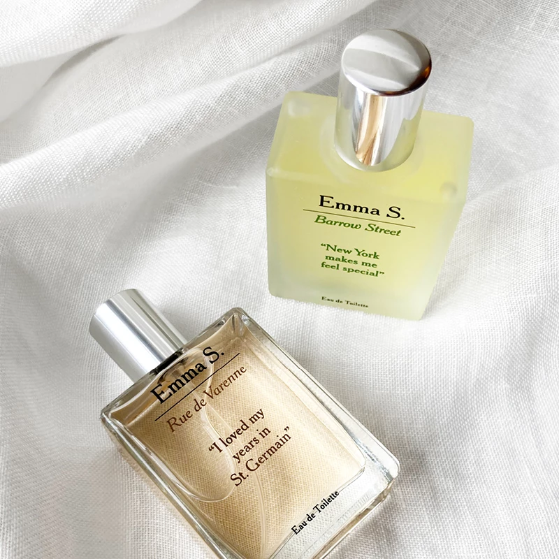 To parfymer fra Emma S.: Rue de Varenne med teksten «I loved my years in St. Germain» og Barrow Street med teksten «New York makes me feel special», plassert på en hvit stoffbakgrunn.