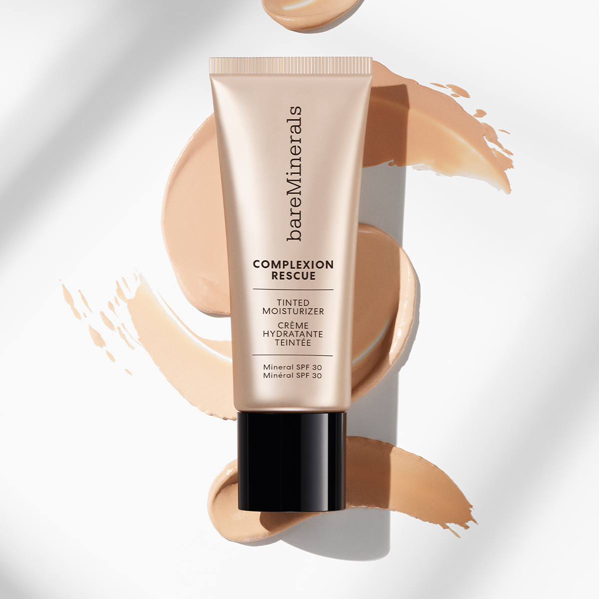 bareMinerals Complexion Rescue Tinted Moisturiser. Voide on beigen värisessä tuubissa, jossa on musta kansi, ja sen etupuolella on teksti ”bareMinerals Complexion Rescue Tinted Moisturiser Crème Hydratante Teintée SPF 30”. Tausta on valkoinen, ja tuotteen takana on useita beigen värisiä siveltimenvedoksia.