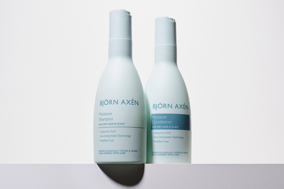 Björn Axén Moisture Shampoo ja Moisture Conditioner. Molemmat tuotteet ovat vaaleansinisissä pulloissa. Pullot seisovat vierekkäin valkoista taustaa vasten.