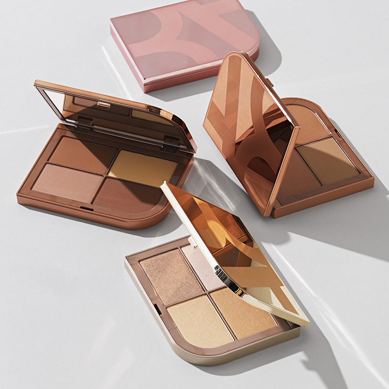 BeautyAct by KICKS -meikkipaletit, jotka ovat avoinna ja joissa on eri sävyjä bronzeria ja highlighteria. Pakkauksissa on eri värejä, muun muassa vaaleanpunainen ja kultainen. Tausta on vaaleanharmaa, ja varjot luovat tyylikkään kuvion.