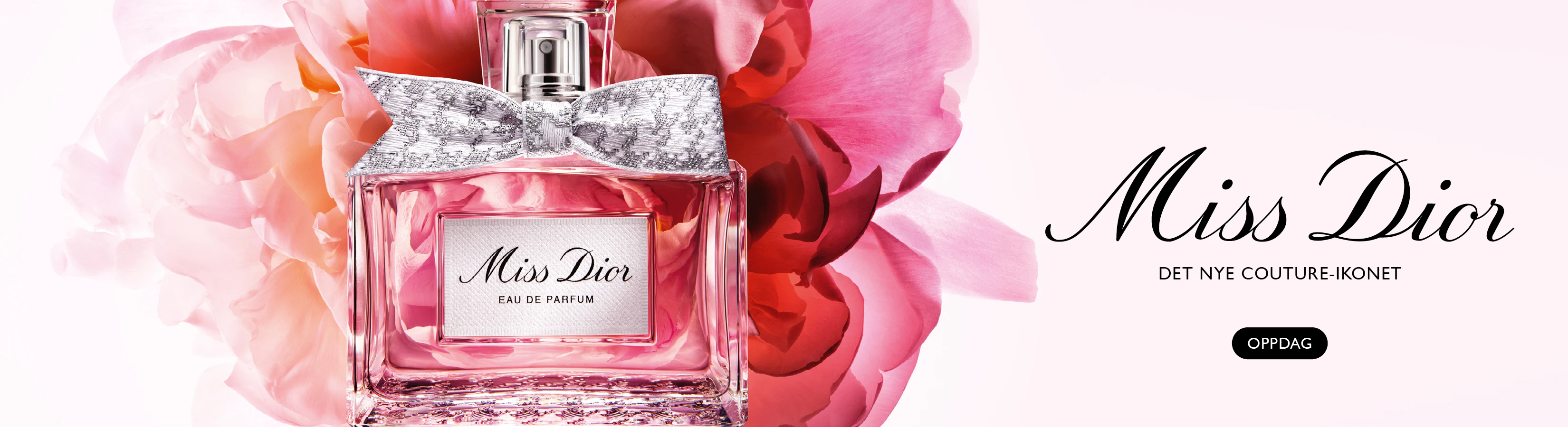 Miss Dior Eau de Parfum-flaske med sølvfarget sløyfe mot rosa blomster. Tekst: 'Miss Dior. Det nye couture-ikonet'. Oppdag.