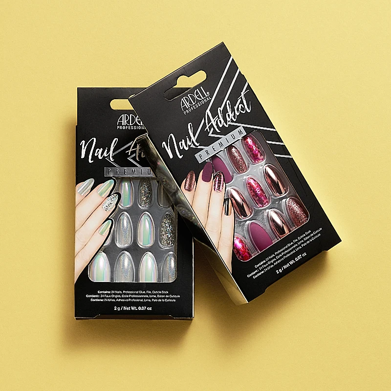 Pakkaukset Ardell Professional Nail Addict Premium irtokynsiä. Toinen pakkaus sisältää hologrammi- ja hopeanvärisiä kynsiä ja toinen pakkaus sisältää kynsiä vaaleanpunaisissa, violeteissa ja kimaltelevissa väreissä. Pakkaukset on sijoitettu keltaiselle taustalle.