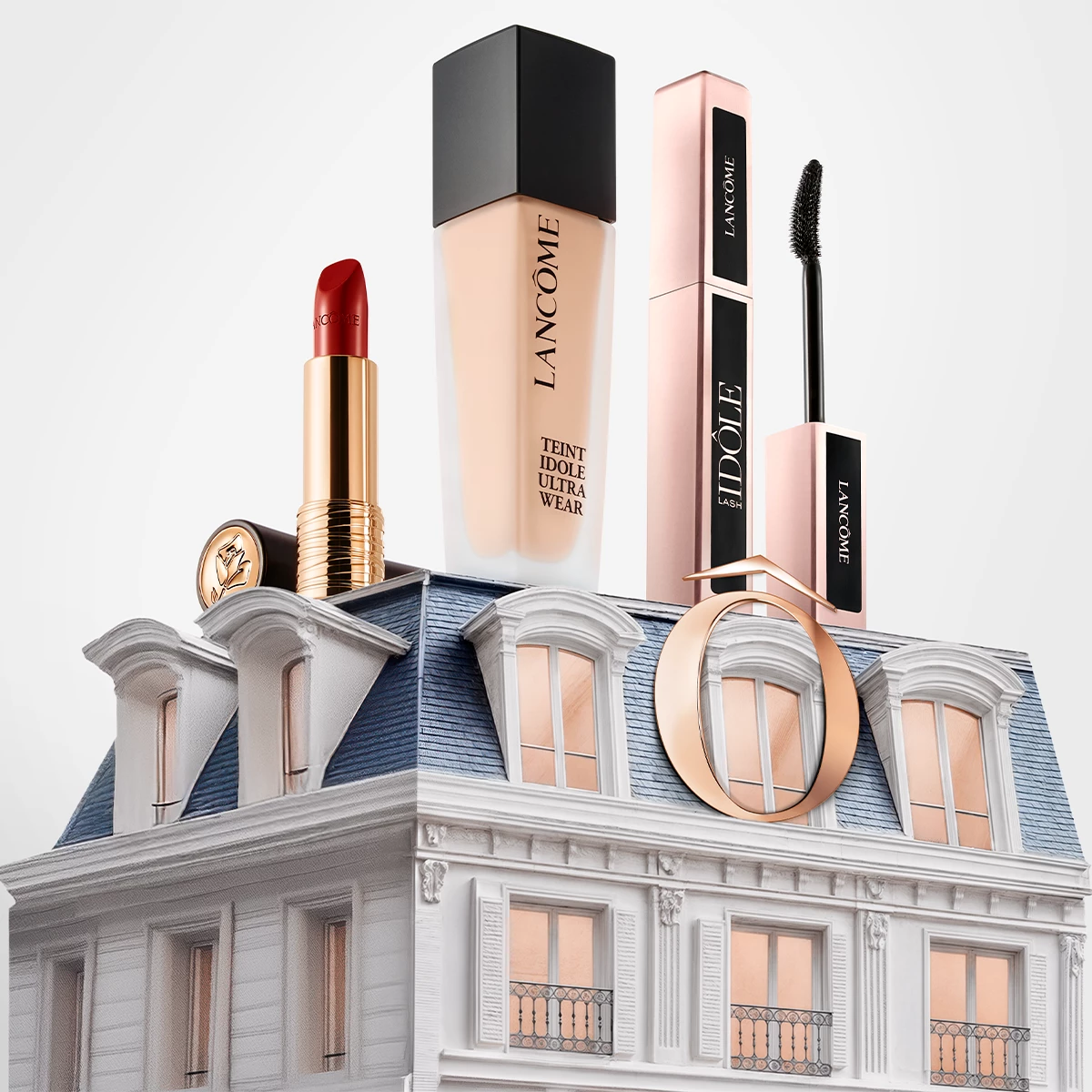 Fire Lancôme sminkeprodukter, inkludert en rød leppestift, foundation, mascara og eyeliner, plassert på taket av en elegant bygning med blått tak og vinduer.