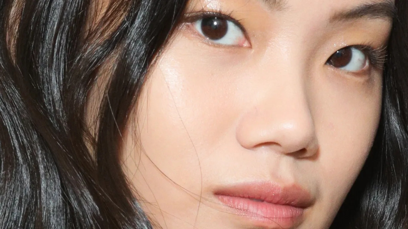 Nærbilde av en kvinne med glatt hud og mørkt hår.