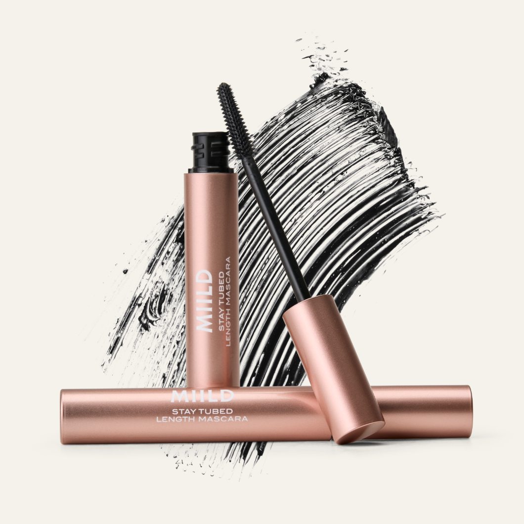 To roségull MIILD STAY TUBED LENGTH MASCARA-mascaraer, den ene åpen med børsten, mot svarte maskaraspor.
