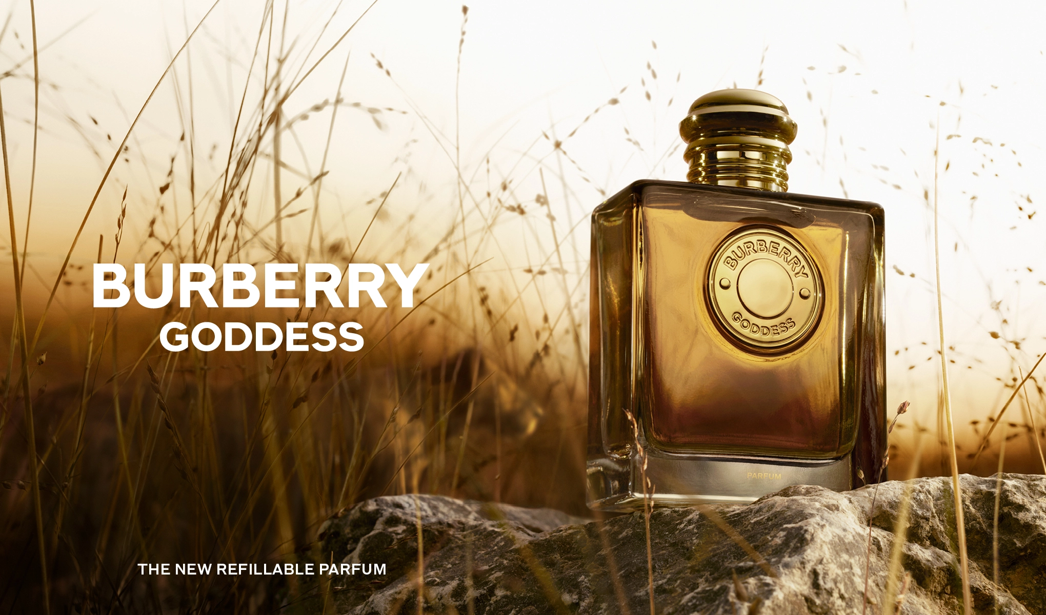BURBERRY GODDESS - Den nye påfyllbare parfymen. En Burberry Goddess parfymeflaske står på en stein omgitt av gress i naturlig lys.