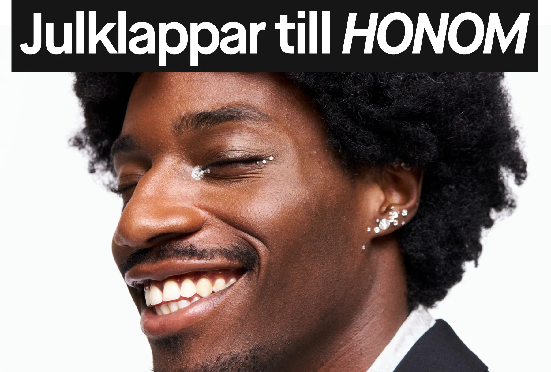 Mörkt, lockigt hår och örhängen med dekorativa glittrande detaljer på vit bakgrund.