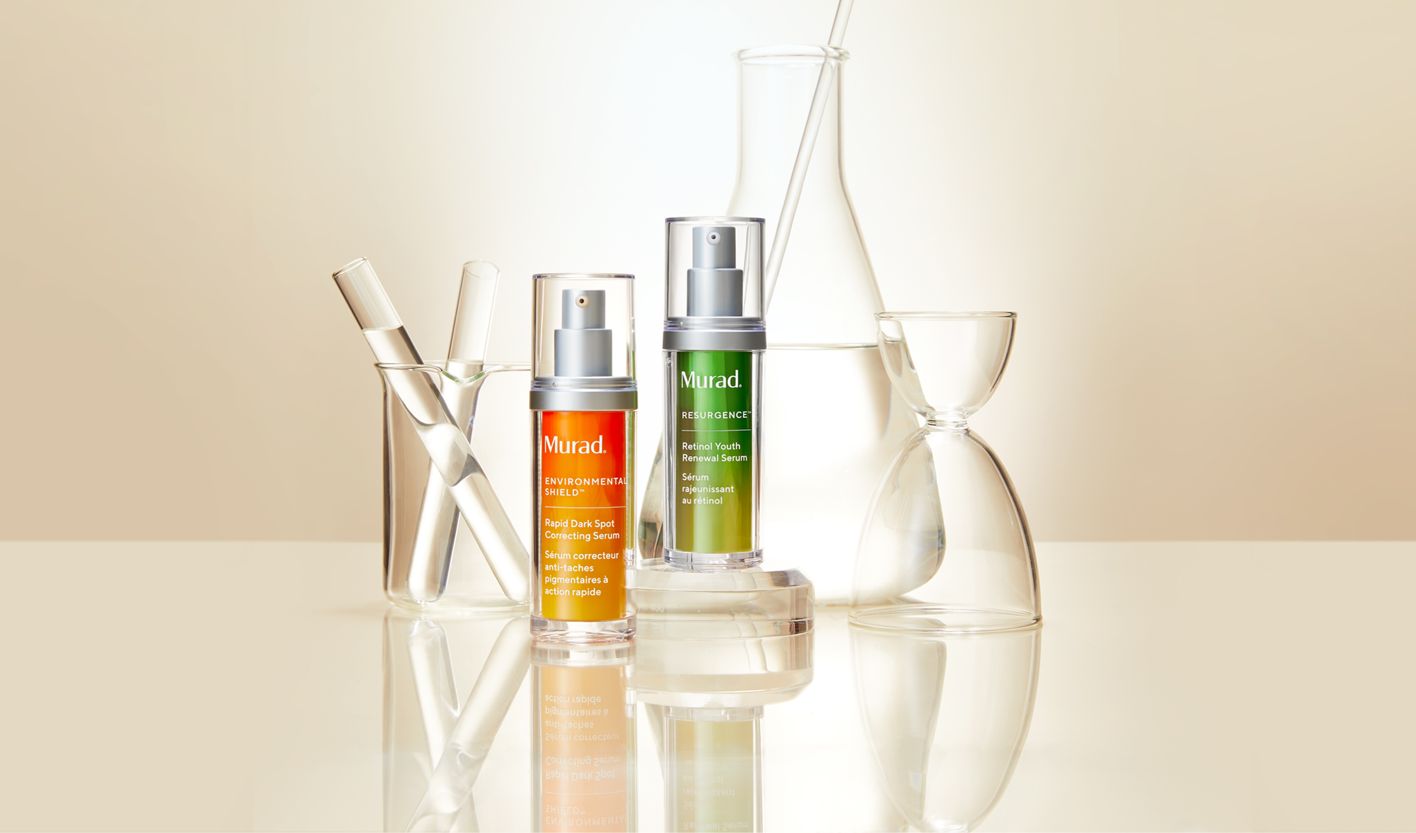 Kaksi Muradin seerumipulloa asetettuna heijastavalle pinnalle. Vasen pullo on oranssi ja siinä on merkintä ”Environmental Shield Rapid Dark Spot Correcting Serum”, kun taas oikea pullo on vihreä ja siinä on merkintä ”Resurgence Retinol Youth Renewal Serum”. Taustalla on erilaisia laboratorion lasitavaroita, kuten koeputkia ja dekantterilaseja, mikä antaa tieteellisen vaikutelman.