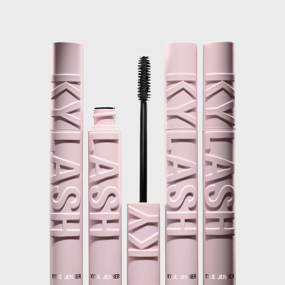Fem lyserosa Kylie Jenner-mascarar er plassert ved siden av hverandre, med en åpen mascarabørste i midten. Mascara-tubene har teksten "KYLASH" i relieff.