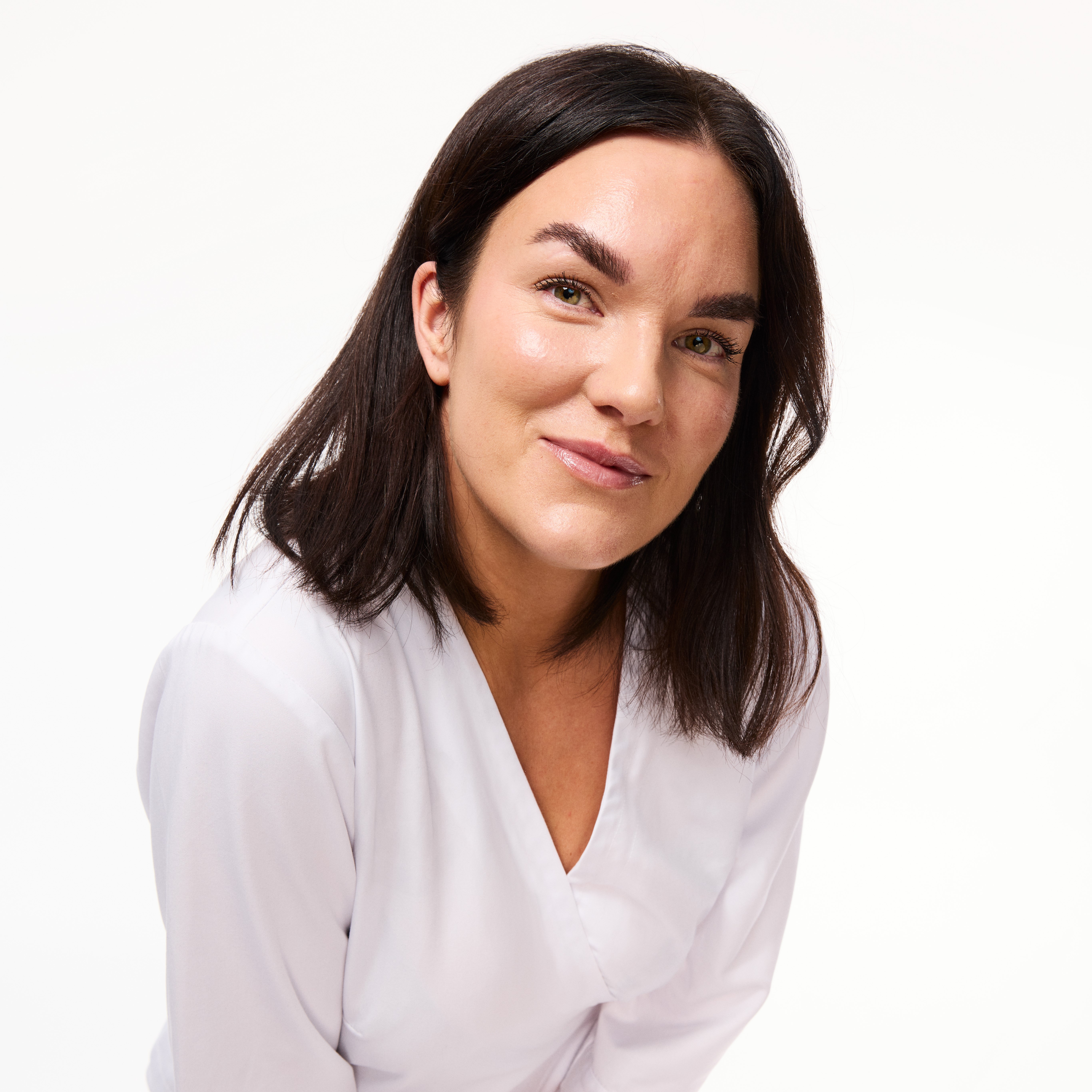 Bild på Ememlie Johansson som lutar sig framåt i en vit rock. 