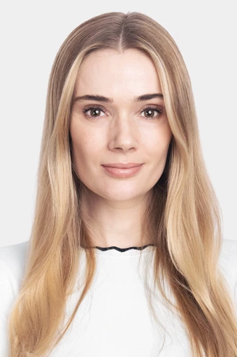 Sara, joka katsoo kameraan ja hymyilee valkoista taustaa vasten