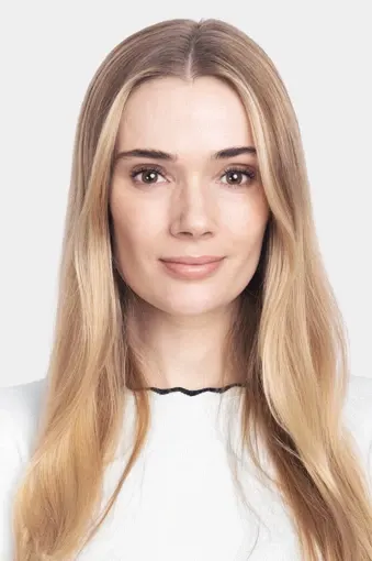 Sara, joka katsoo kameraan ja hymyilee valkoista taustaa vasten