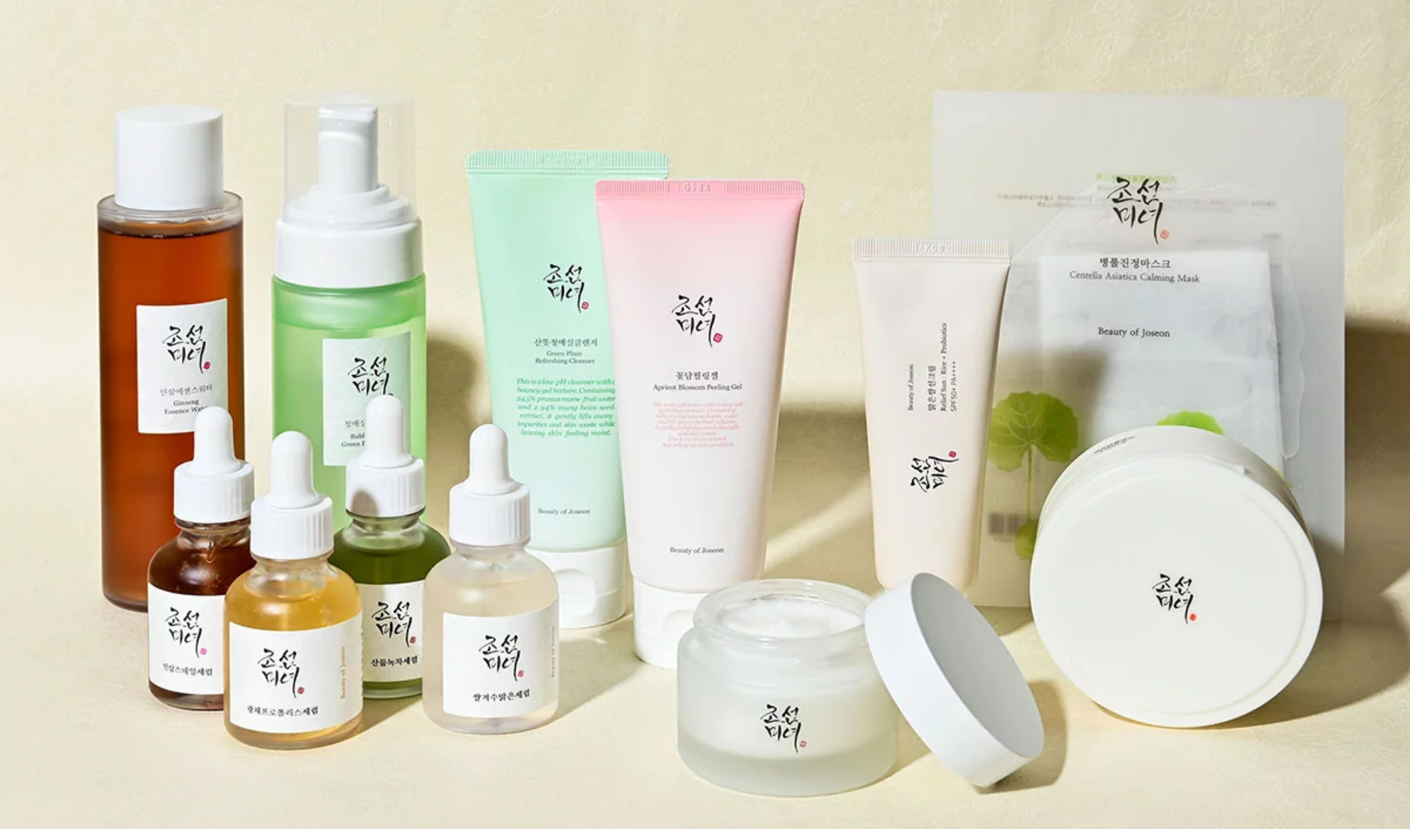 Et utvalg hudpleieprodukter fra merket Beauty of Joseon. De er plassert på en lys flate med beige bakgrunn. Emballasjen har et minimalistisk design med koreansk tekst og enkle etiketter.
