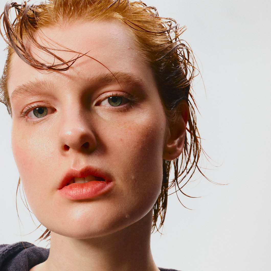 En person med vått hår mot en hvit bakgrunn.