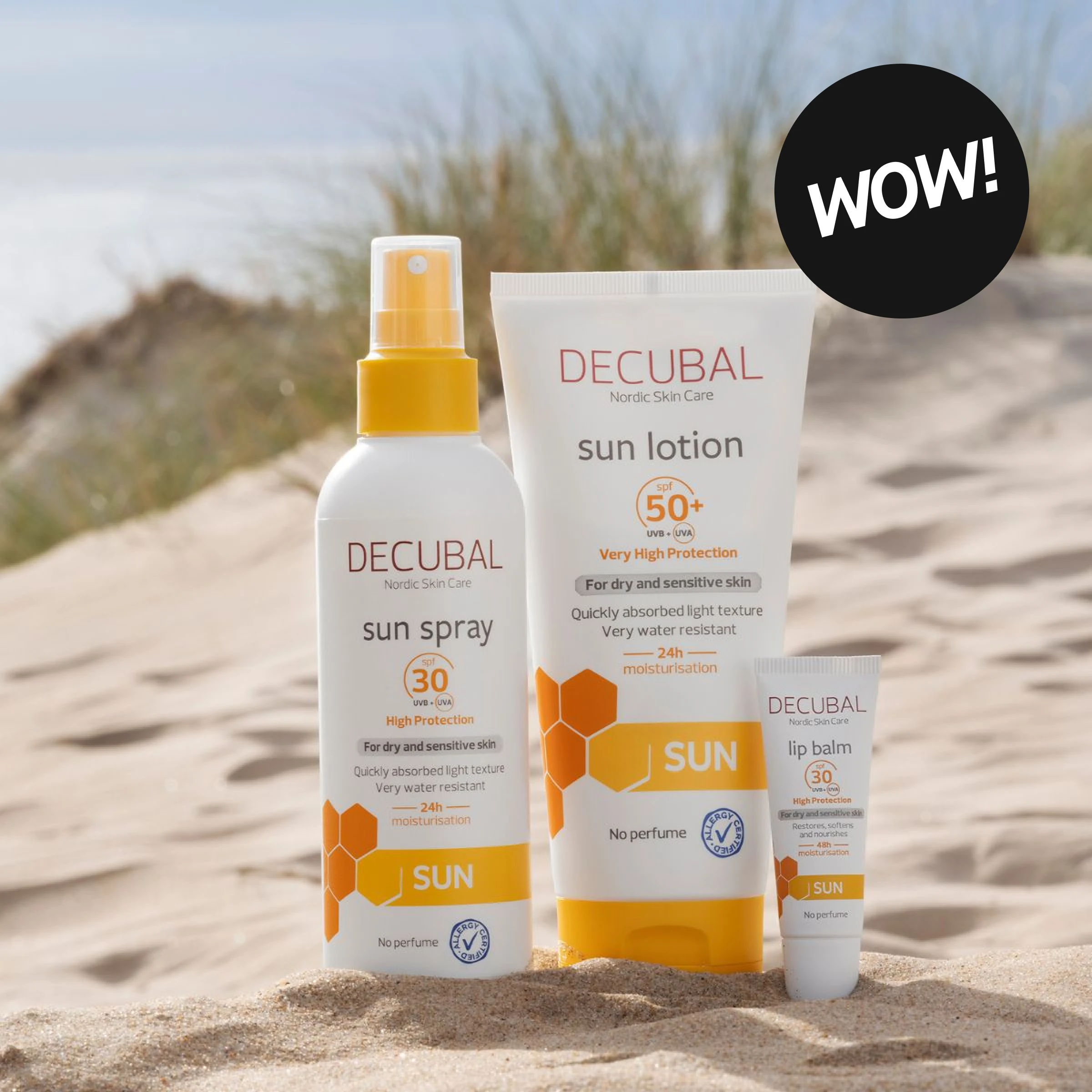Decubal solskydd med “sun spray SPF 30”, “sun lotion SPF 50+” och “lip balm SPF 30” placerade i sand på strand, med texten “WOW!”.
