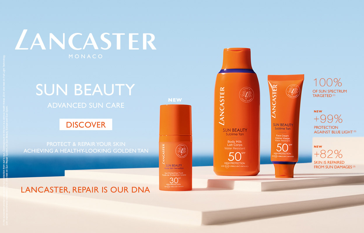 Kolme Lancasterin aurinkosuojatuotetta, jotka on sijoitettu valkoiselle pinnalle ja taustalla on sininen taivas. Kuvan tekstissä lukee ”Sun Beauty Advanced Sun Care”, ”Discover”, ”Protect & Repair Your Skin Achieving a Healthy-Looking Golden Tan”, ”Lancaster, Repair is Our DNA” sekä tietoa aurinkosuojan spektristä ja sinisen valon suojasta.