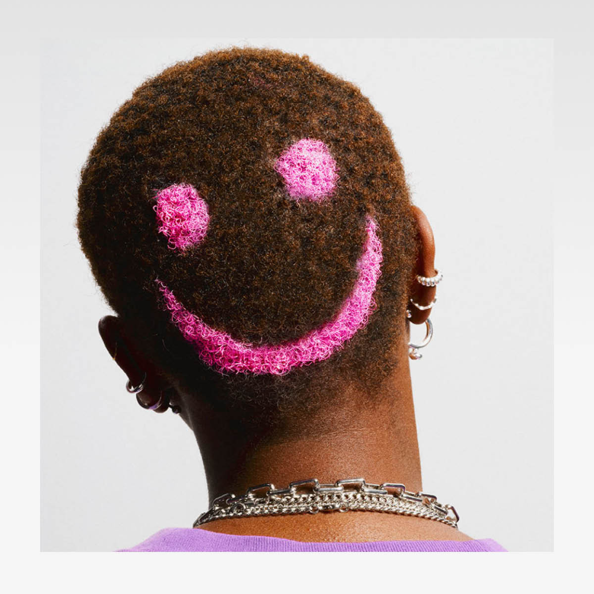 bakhodet på person med brunt hår og farget rosa smiley ansikt i håret