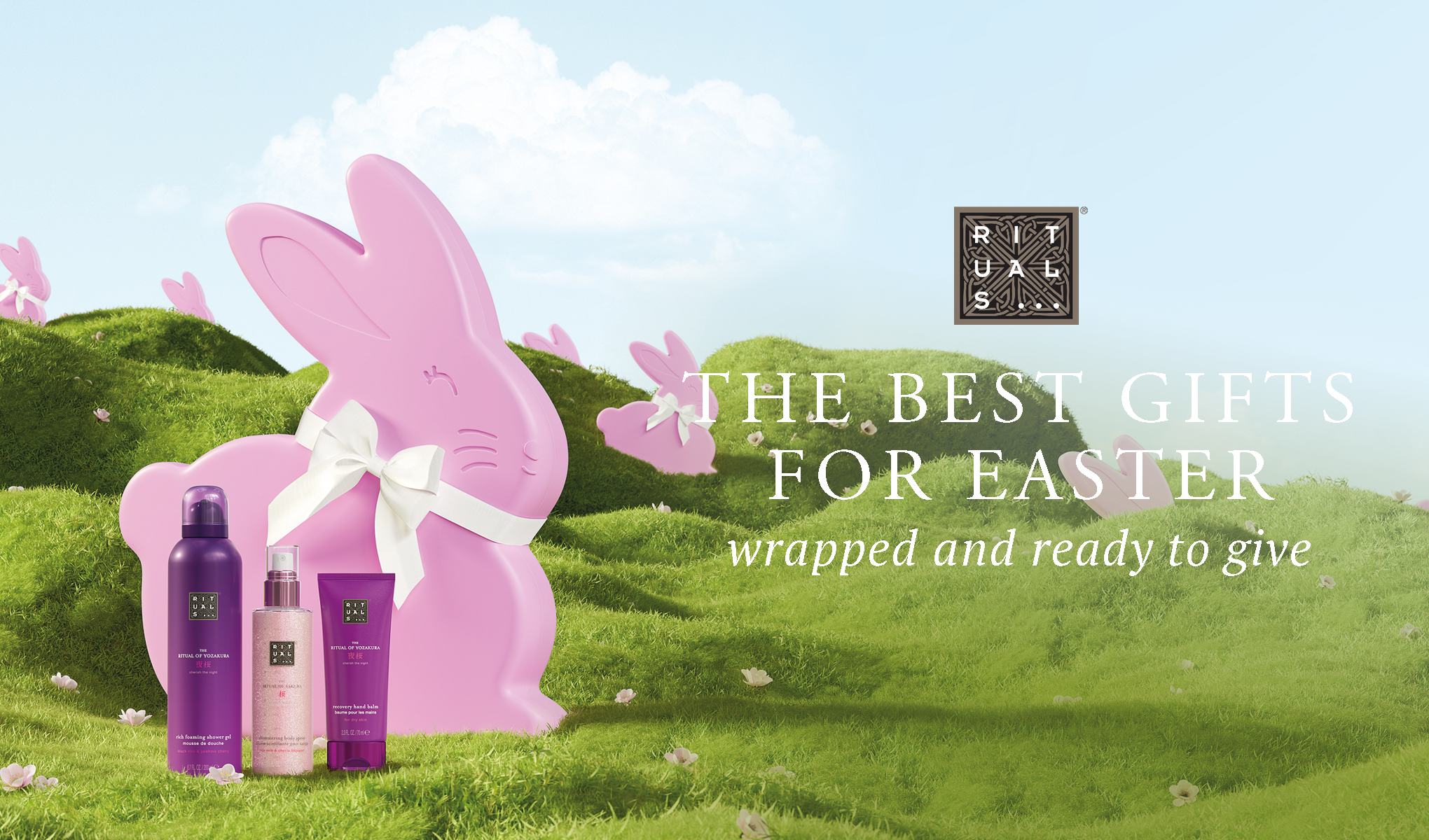 Rituals-produkter, inkludert dusjgel, kroppsspray og håndkrem, ved siden av en rosa kanin på grønt gress. Tekst: "THE BEST GIFTS FOR EASTER wrapped and ready to give".