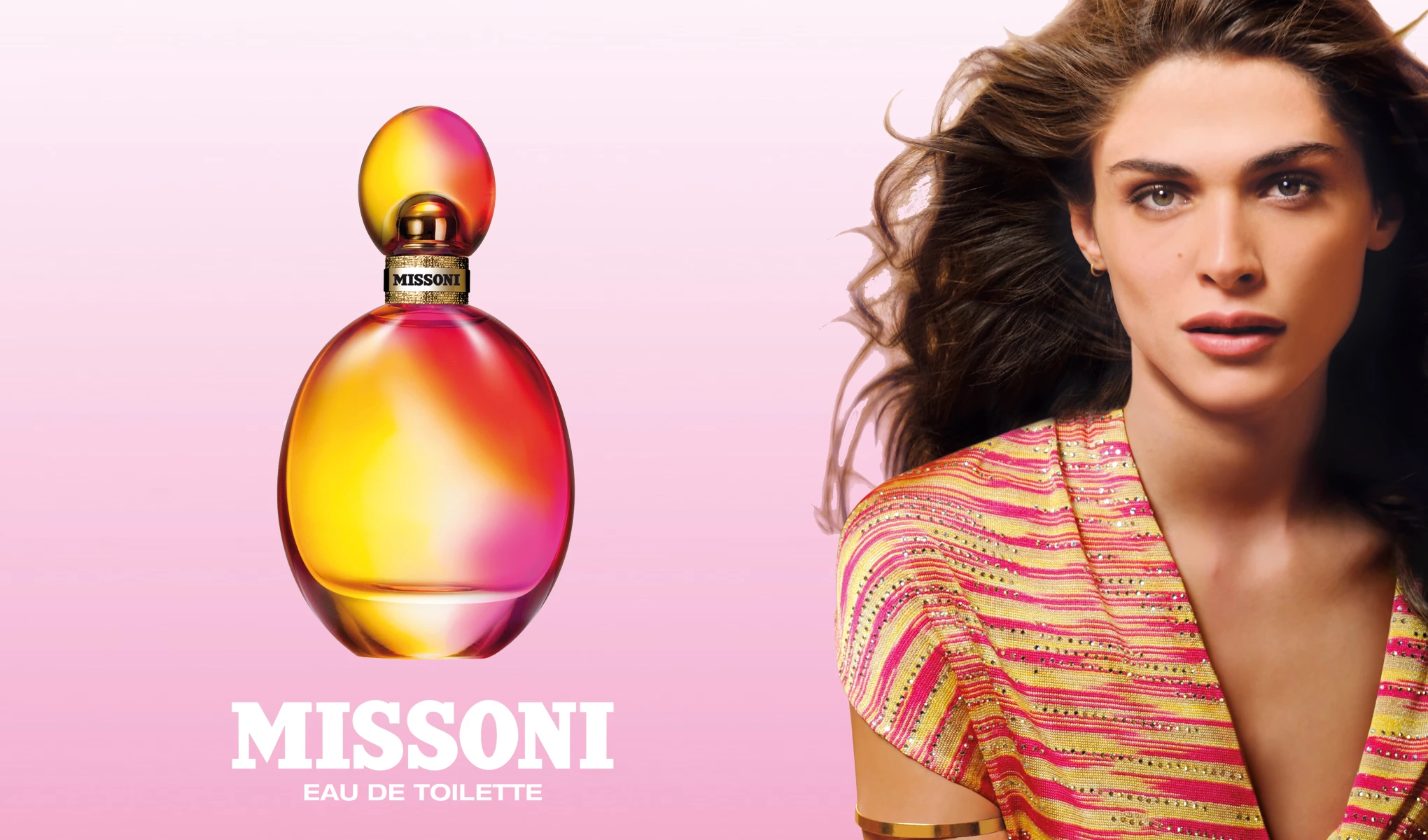 En parfymeflaske fra Missoni med navnet «Eau de Toilette». Flasken har et fargerikt design med innslag av rosa, oransje og gult. Til høyre for flasken ser vi en kvinne med langt, krøllete hår iført en fargerik genser. Bakgrunnen er rosa, og teksten på bildet lyder «Missoni Eau de Toilette».