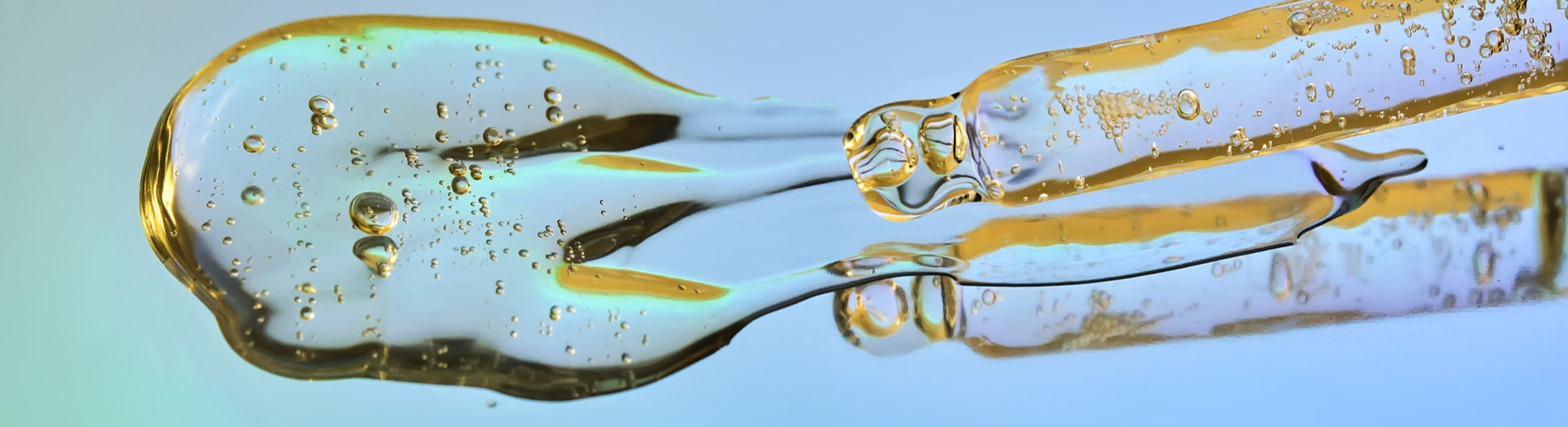 Pipett med serum på en spegelblank blå turkos yta. 