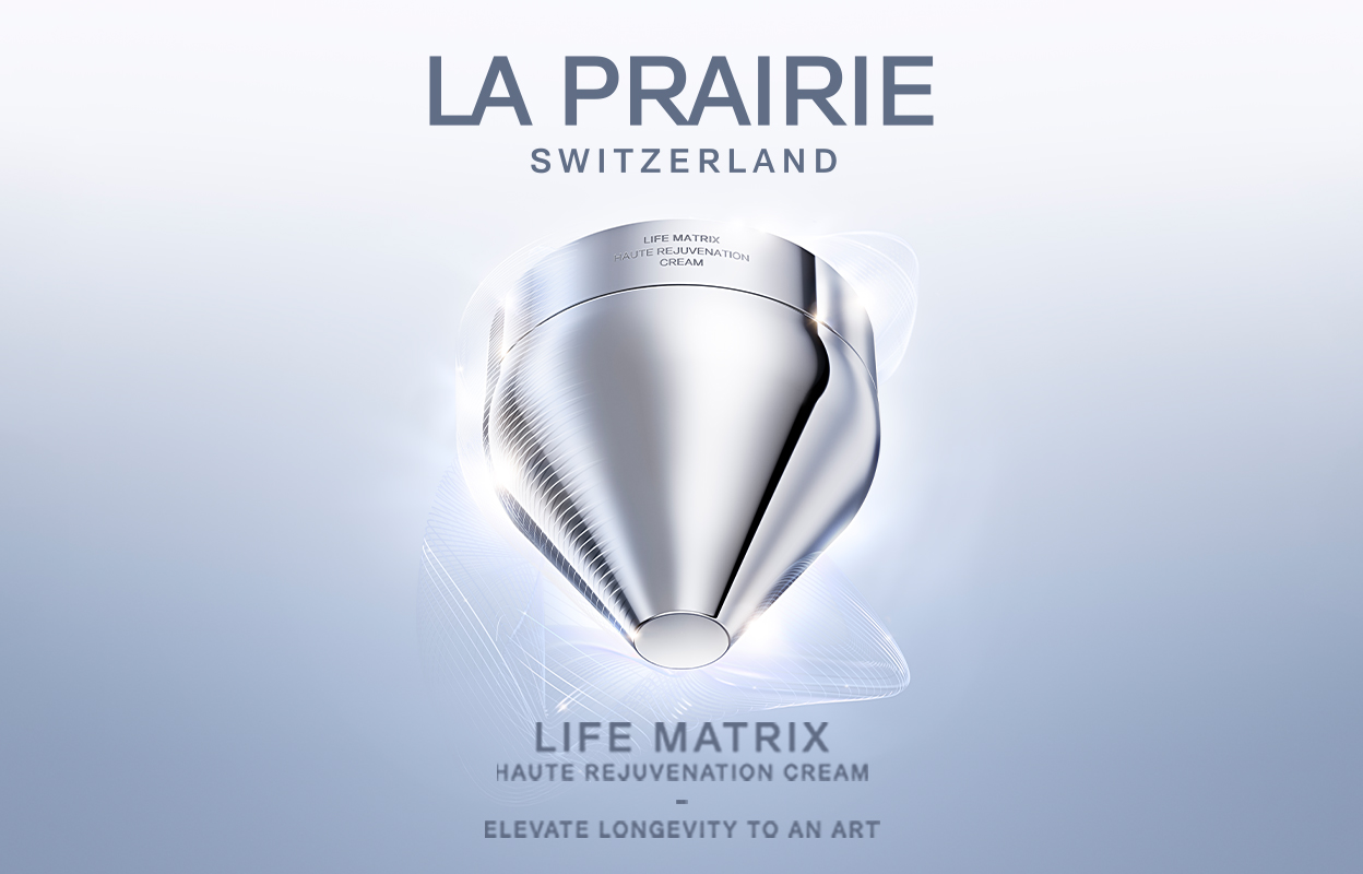 Hopeanvärinen purkki La Prairien Life Matrix Haute Rejuvenation -voidetta vaaleansinisellä pohjalla. Kuvassa on teksti ”La Prairie Switzerland” ja ”Life Matrix Haute Rejuvenation Cream - Elevate Longevity to an Art”. Taustalla on futuristinen ja tyylikäs muotoilu.