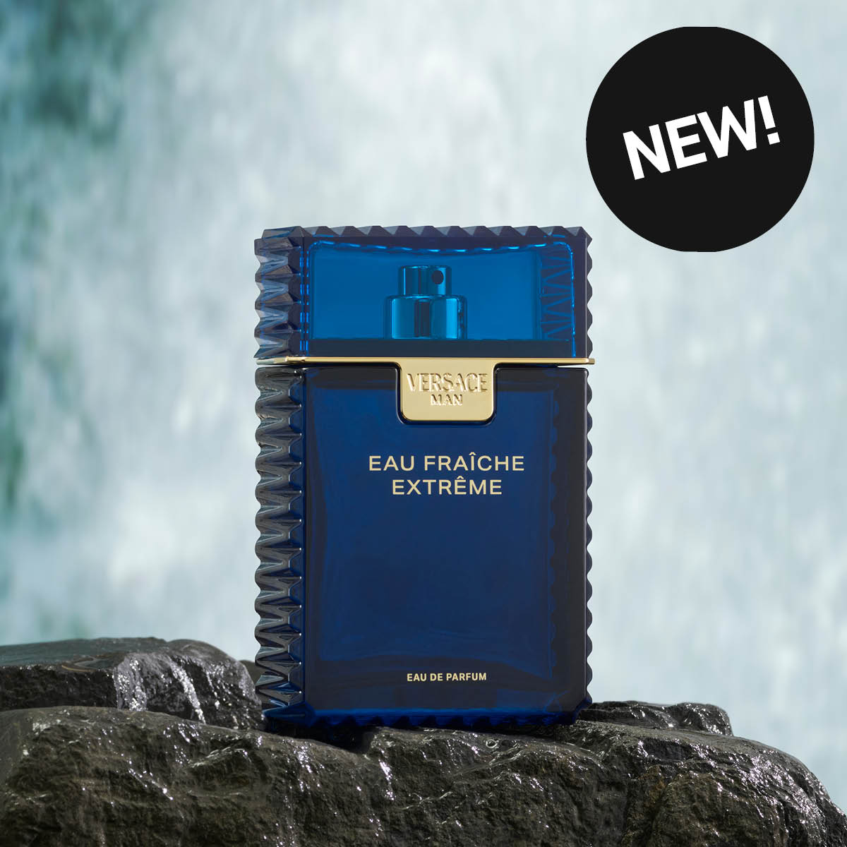 Sininen Versace Man Eau Fraîche Extrême -hajuvesipullo vesiputouksen edessä. Tarra, jossa lukee "NEW!"