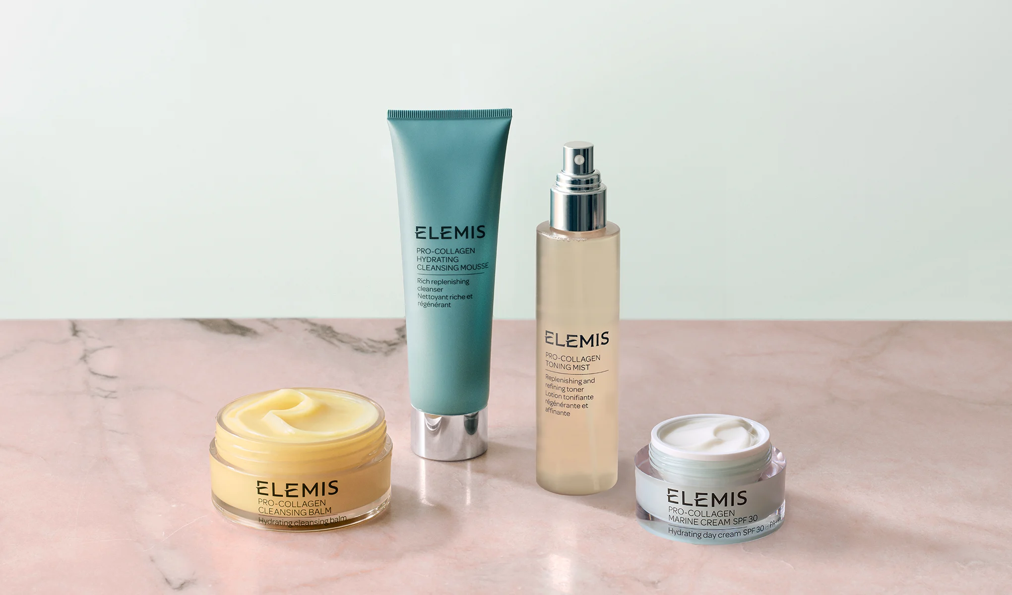 Elemis Pro-Collagen hudvårdsprodukter (rengöringsbalm, rengöring, toner och ansiktskräm) på marmoryta.