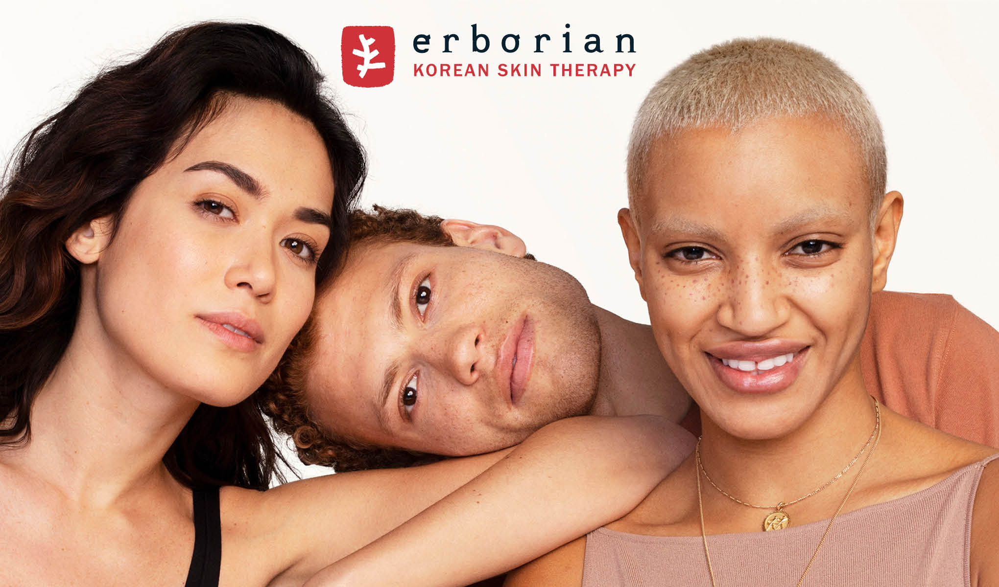 Kolme ihmistä poseeraa yhdessä valkoisen taustan edessä. Heillä on erilaiset ihonvärit ja hiustyylit. Kuvan yläreunassa näkyy ”Erborian Korean Skin Therapy” -logo.