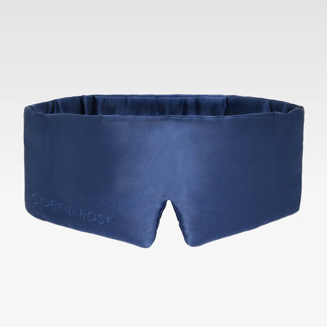 Tummansininen satiininen DORE & ROSE -unimaski pehmeällä topatulla muodolla vaaleanharmaalla taustalla. Tyylikäs sleep mask parempaan uneen ja mukavuuteen.