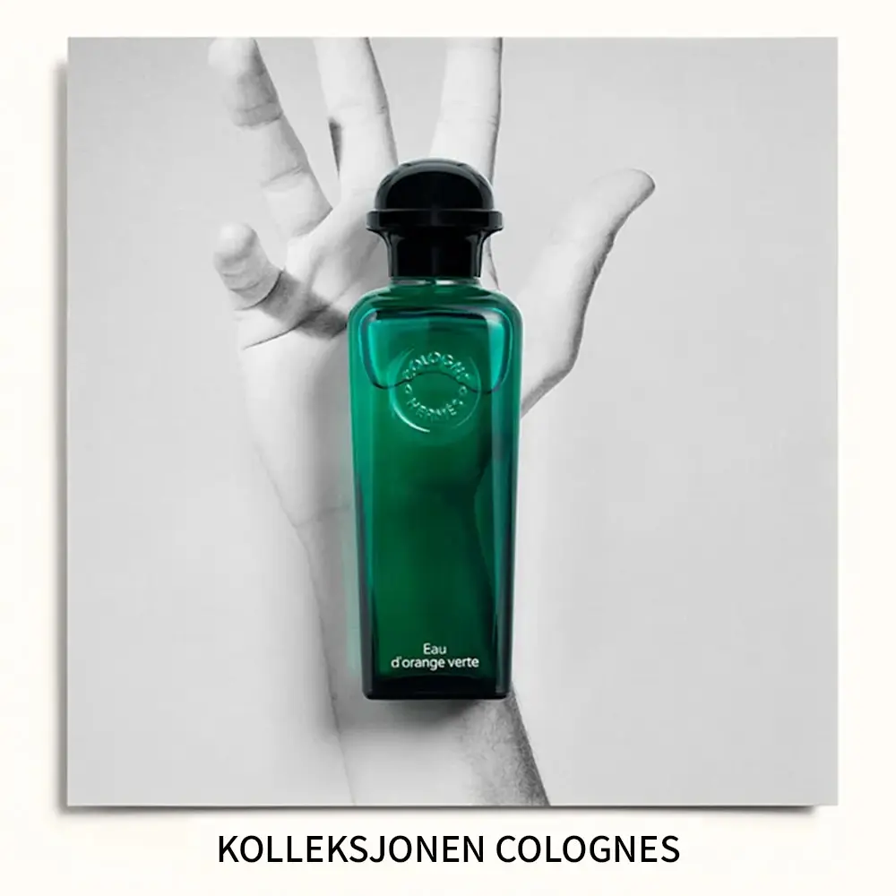 «Kolleksjonen Colognes». Parfymeflasken Hermès Eau d’Orange Verte plassert foran et svart-hvitt bilde av en hånd.