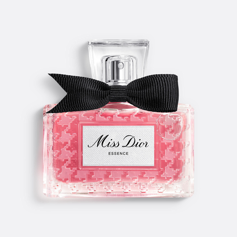 Miss Dior Essence-parfym i rosa glasflaska med svart rosett och transparent kork mot vit bakgrund.