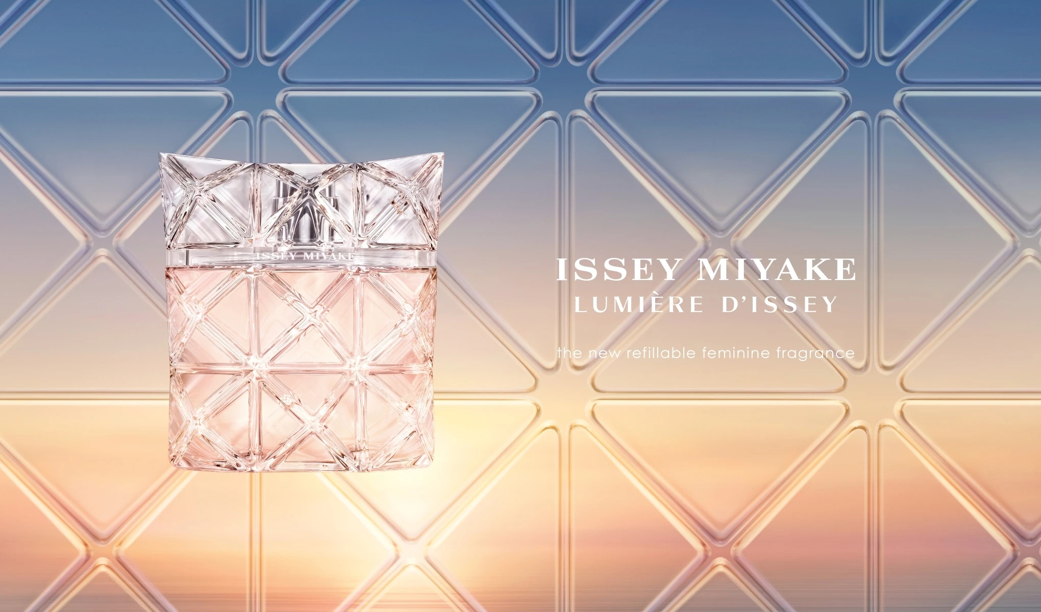 Parfymflaska från Issey Miyake med namnet “ISSEY MIYAKE LUMIÈRE D’ISSEY” i rosa tonat glas med geometriskt mönster. I bilden syns även texten “the new refillable feminine fragrance” mot en bakgrund i gradient av blått och varmt ljus.