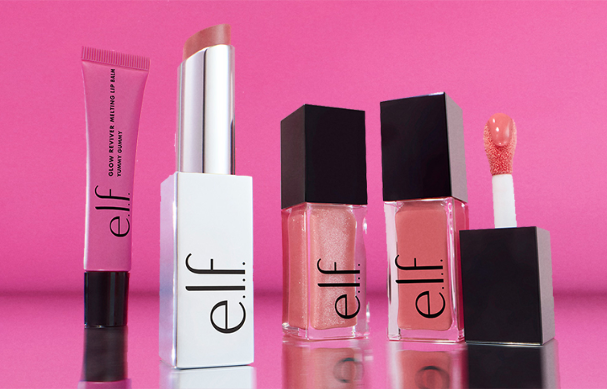 e.l.f. kosmetikprodukter mot en rosa bakgrund. Bilden innehåller ett läppbalsam, ett läppstift och två läppglans.