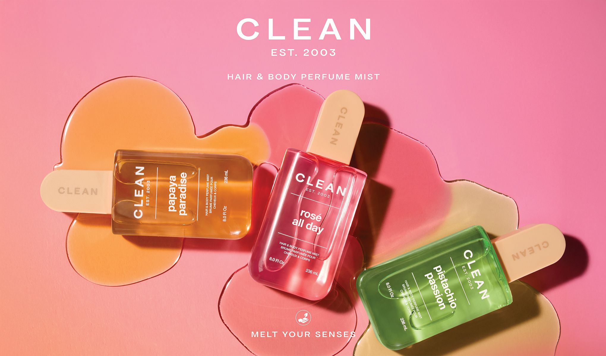 Kolme CLEAN Hair & Body Perfume Mist -pulloa on aseteltu vaaleanpunaiselle taustalle, jossa on oranssia, pinkkiä ja vihreää väriä. Tekstit “CLEAN EST. 2003”, “HAIR & BODY PERFUME MIST”, “papaya paradise”, “rosé all day”, “pistachio passion”, “8.0 FL OZ / 236 mL” ja “MELT YOUR SENSES” näkyvät selkeästi tuotteissa ja kuvassa.