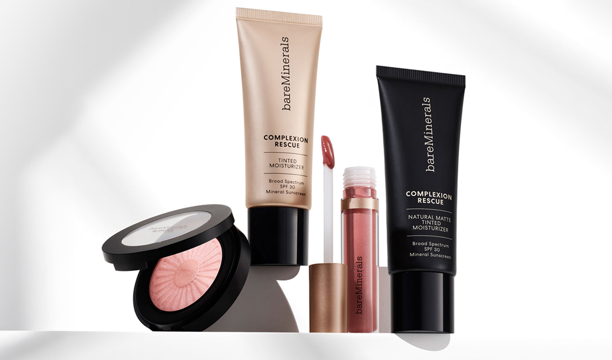 Utvalt sortiment av bareMinerals-smink med Complexion Rescue tinted moisturizer, matt variant, läpprodukt och rosa rouge mot ljus bakgrund.