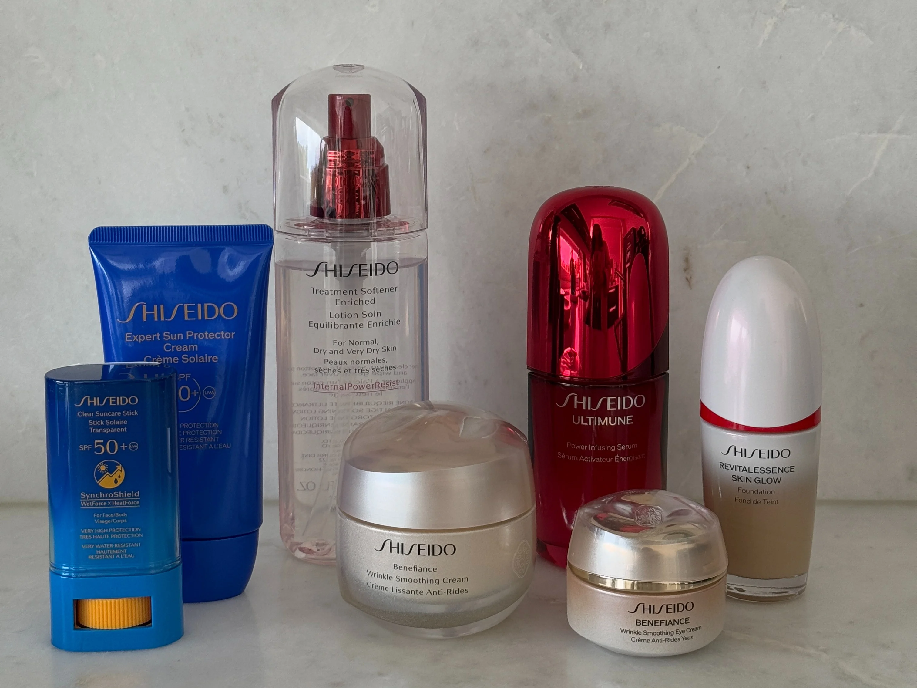 En samling av Shiseido hudvårdsprodukter inklusive serum, ansiktskräm och solskydd, arrangerade på en marmoryta.