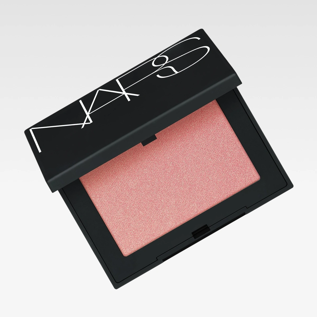 NARS rouge i svart makeupdosa med rosa puder mot ljusgrå bakgrund. Synlig text inkluderar “NARS”.