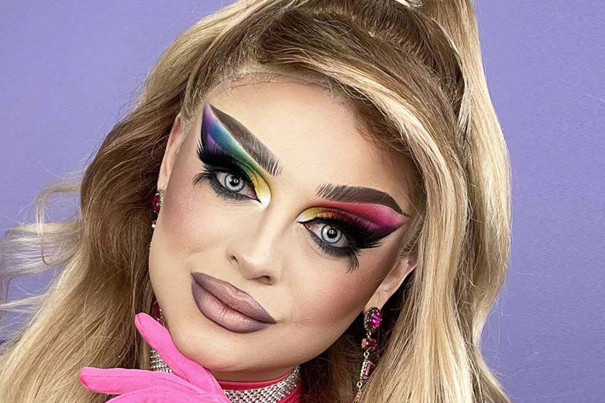 En person med suddat ansikte och blont hår står mot en lila bakgrund.