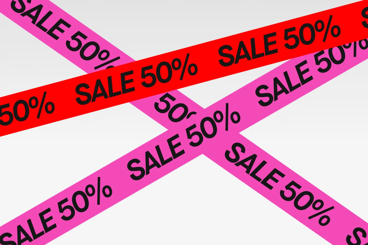 "Färgade band i rosa och rött med svart text 'SALE 50%' korslagda över en ljus bakgrund."
