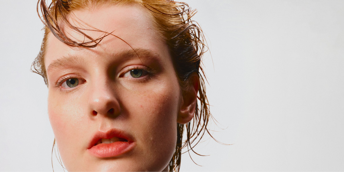 Henkilö, jolla on märät hiukset valkoista taustaa vasten.