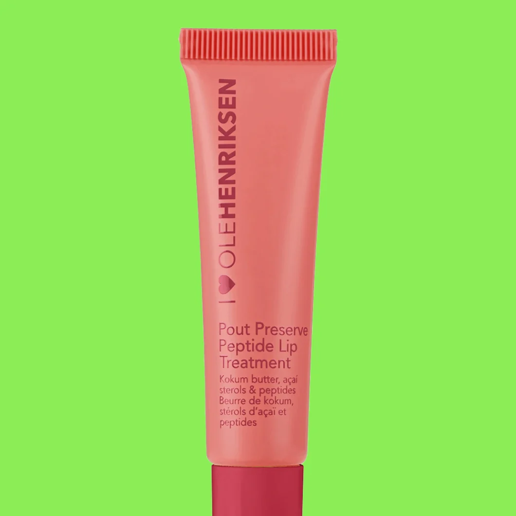 Tube merket “OLEHENRIKSEN Pout Preserve Peptide Lip Treatment Kokum butter, açaí sterols & peptides” mot grønn bakgrunn.