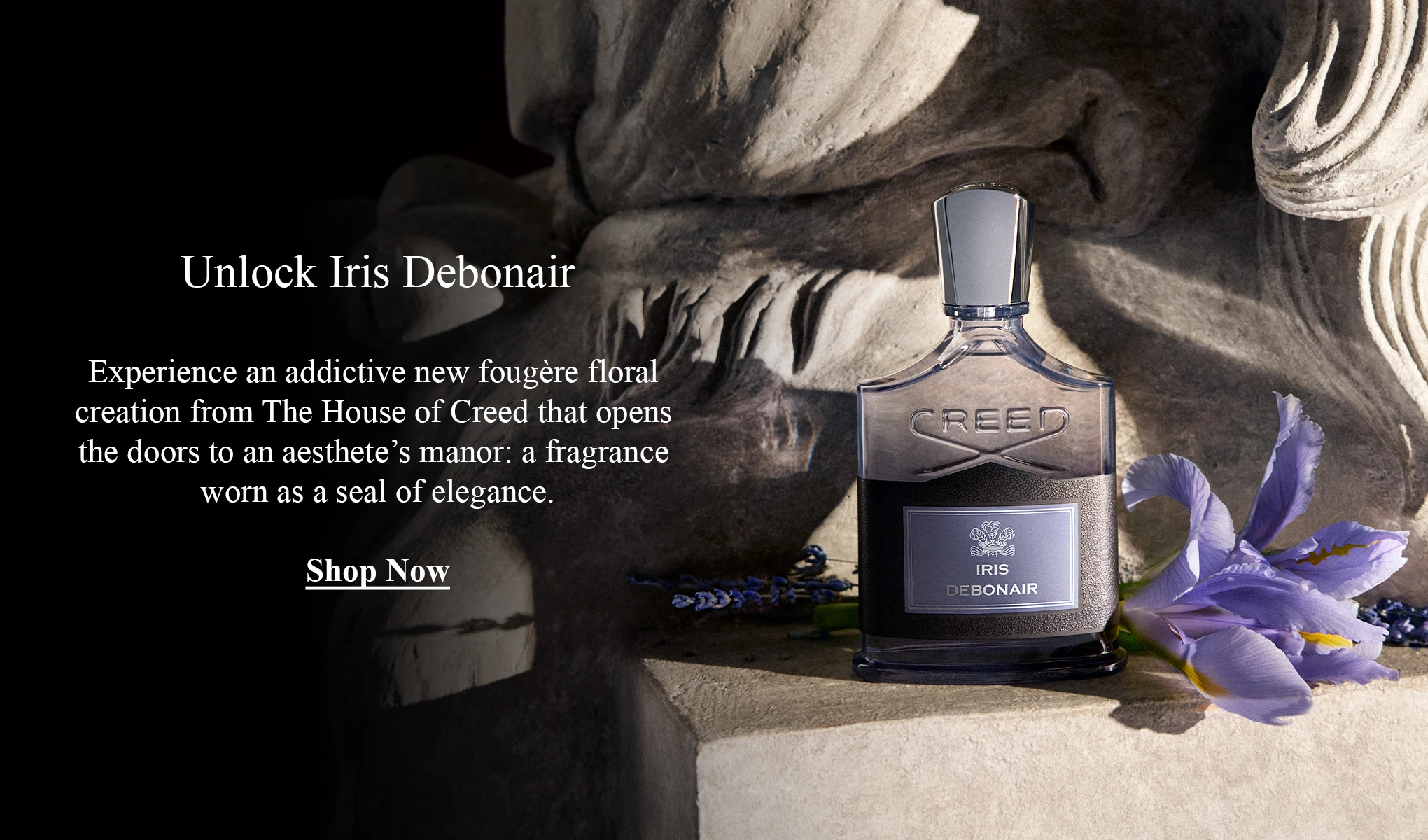 Creed Iris Debonair -tuoksupullo iiriskukkien vieressä. Teksti: ”Unlock Iris Debonair. Koe koukuttava uusi fougère-kukkaistuoksu The House of Creediltä – eleganssin sinetti. Shop Now.”