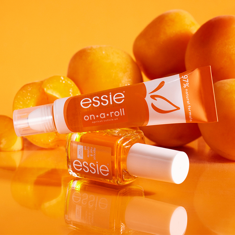 Två nagelvårdsprodukter från Essie placerade mot en orange bakgrund med aprikoser.