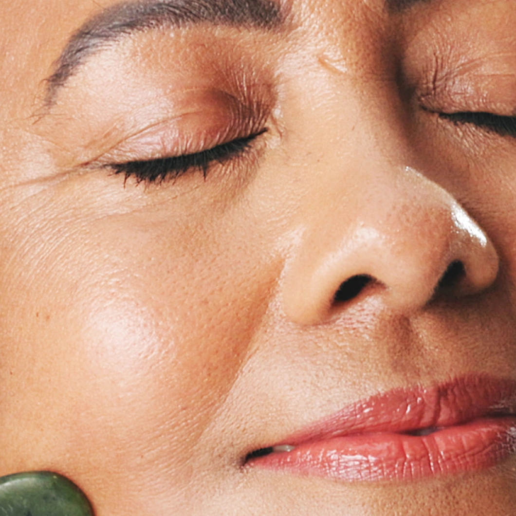 Nærbilde av ansikt med lukkede øyne og glatt hud med naturlig glød.