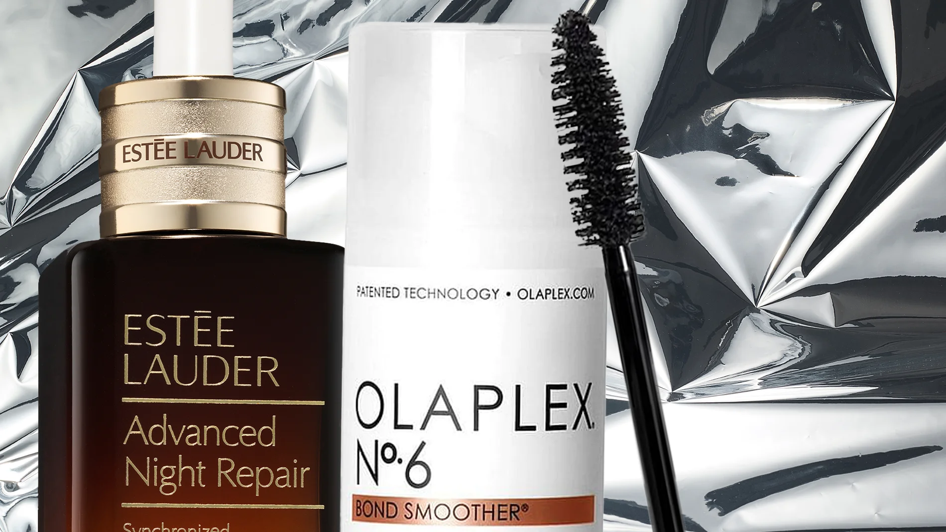 Lähikuva kolmesta kauneustuotteesta hopeisella taustalla: Estée Lauder Advanced Night Repair -seerumi, Olaplex No.6 Bond Smoother ja musta ripsiväriharja.