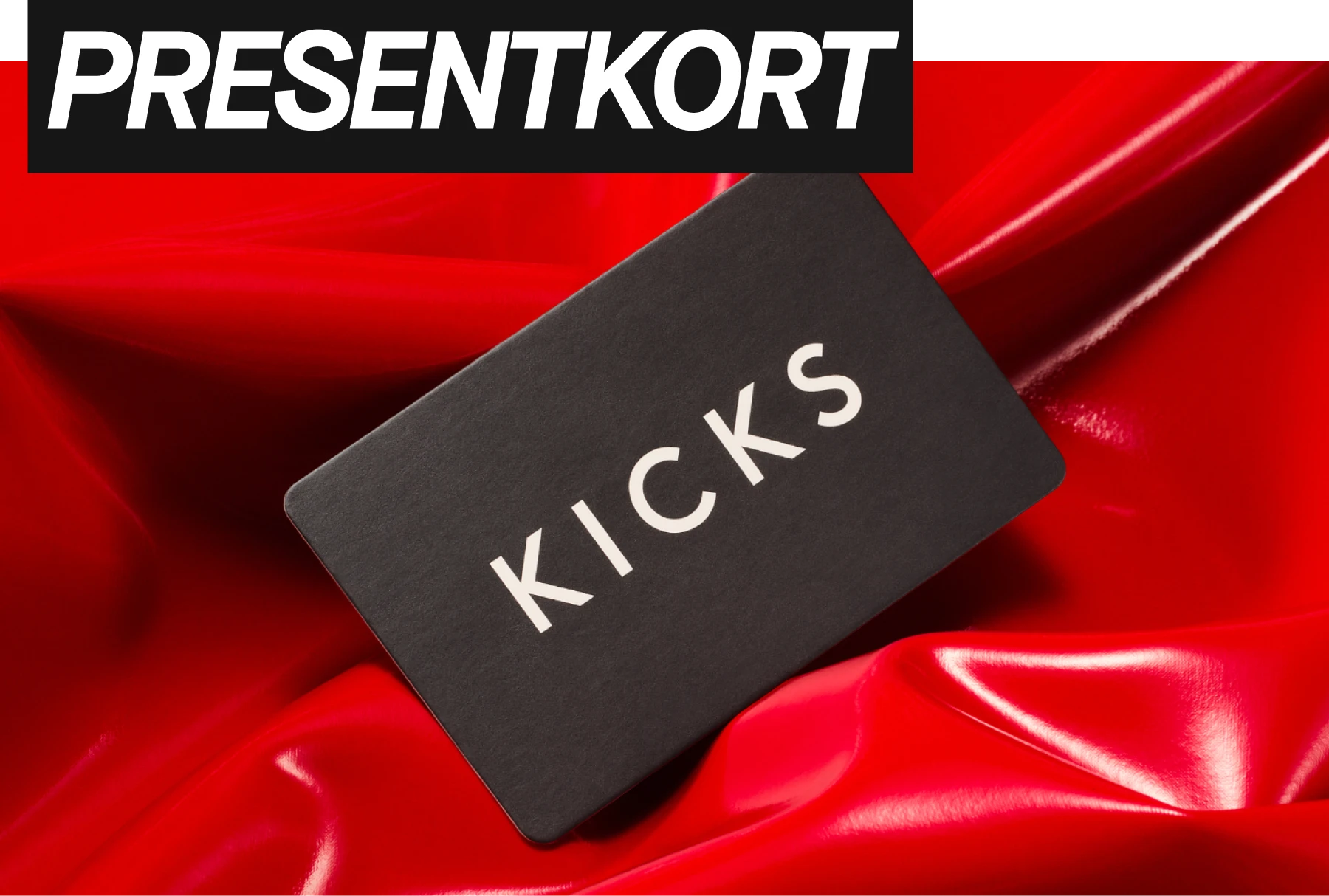Presentkort  som ligger mot röd bakgrund från KICKS med texten Presentkort